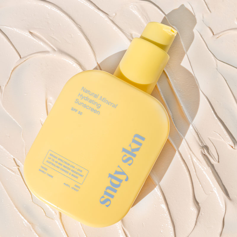 Yellow bottle of 'snyd skin' sunscreen on a textured beige background